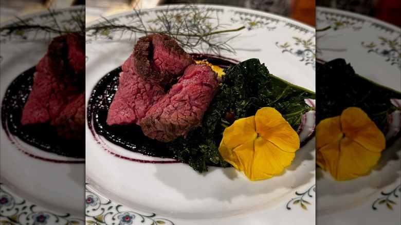 Plated roast beef with greens and yellow flower