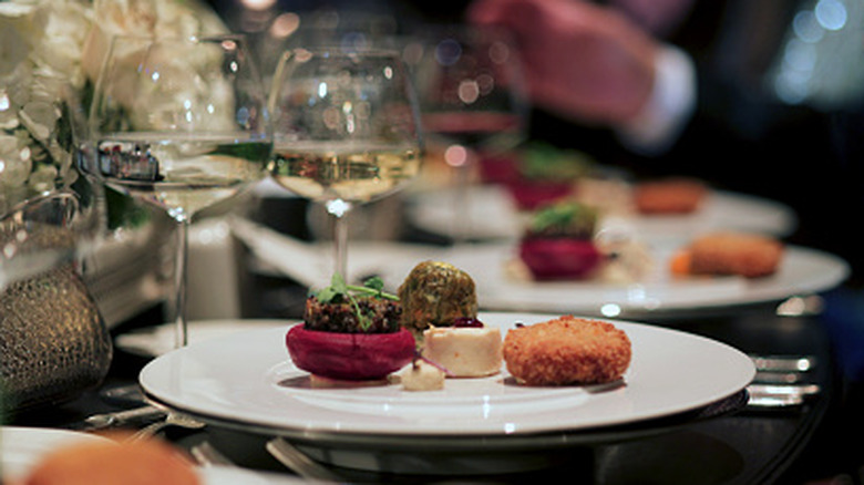 Plated gourmet dish with wine glasses in the background