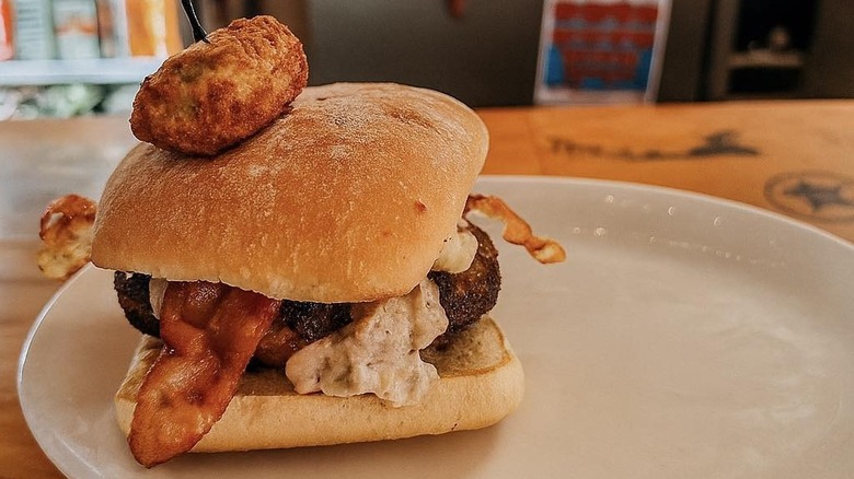 Plated hamburger with bacon topped with fried popper