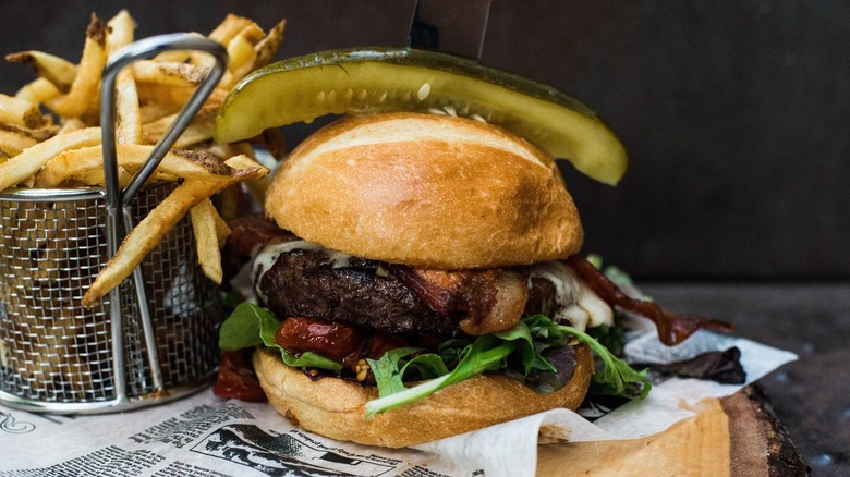Hamburger topped with a pickle and fries basket