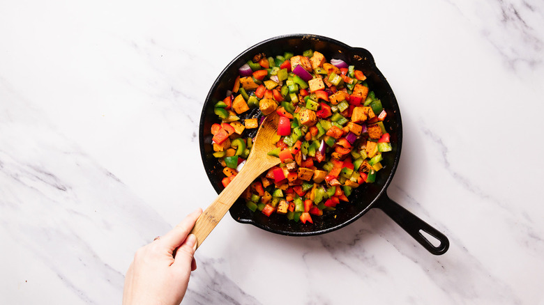 Skillet with cooked sweet potatoes, bell peppers and onions