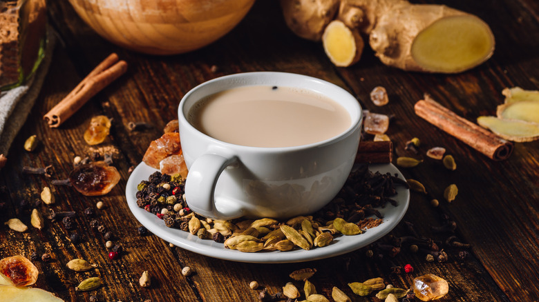 a mug of masala chai surrounded by ingredients