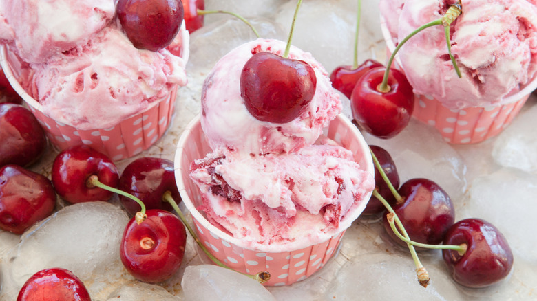 Cherry flavored ice cream in paper cups surrounded by cherries