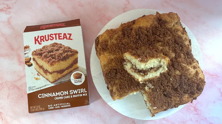 a Krusteaz Cinnamon Swirl Crumb Cake Mix box beside the prepared cake