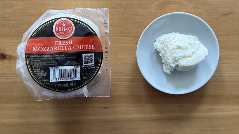 A package of Primo Taglio fresh mozzarella beside a bowl with a chunk of the cheese