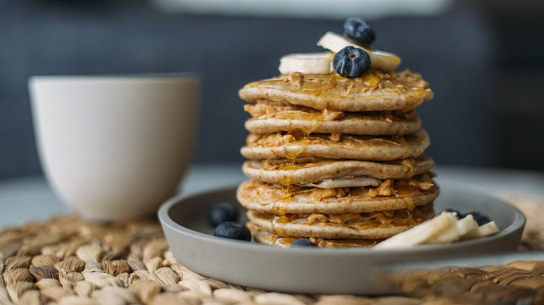 Stack of pancakes with blueberries and bananas on gray ceramic dish