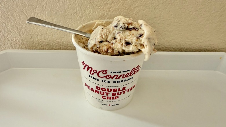 Open pint of McConnell's Double Peanut Butter Chip ice cream with a spoon.
