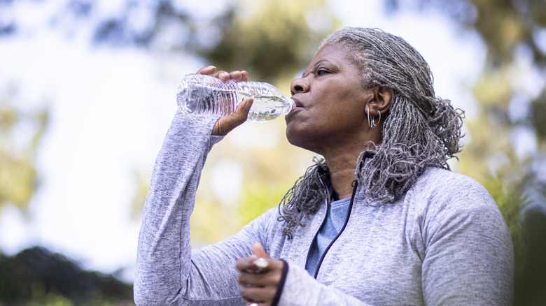 woman drinking from a plastic water bottle while outdoors