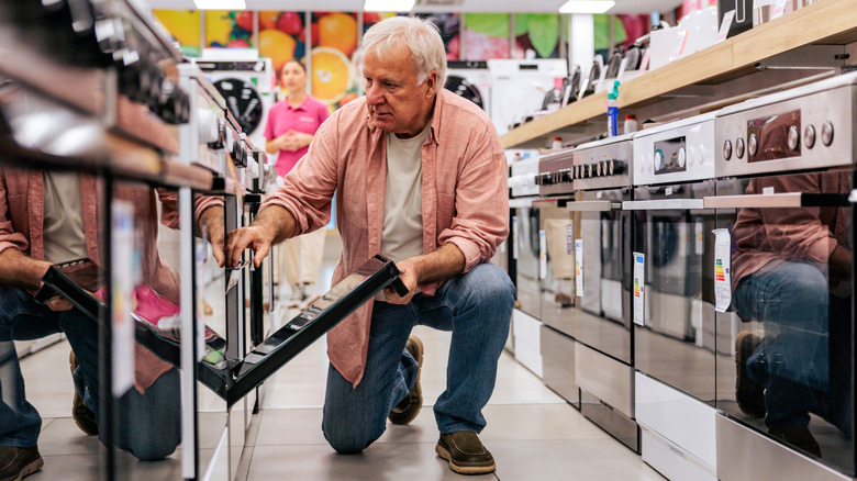 A person crouched down, shopping for a stove.