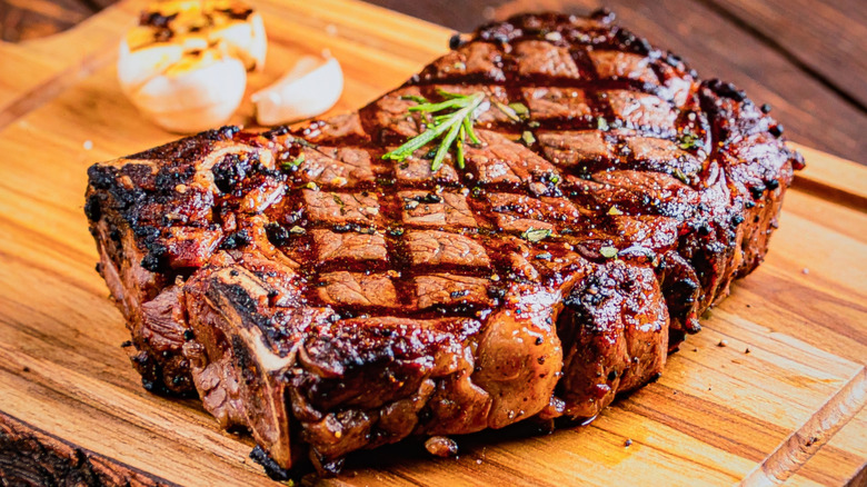 A cooked ribeye steak on a wooden board