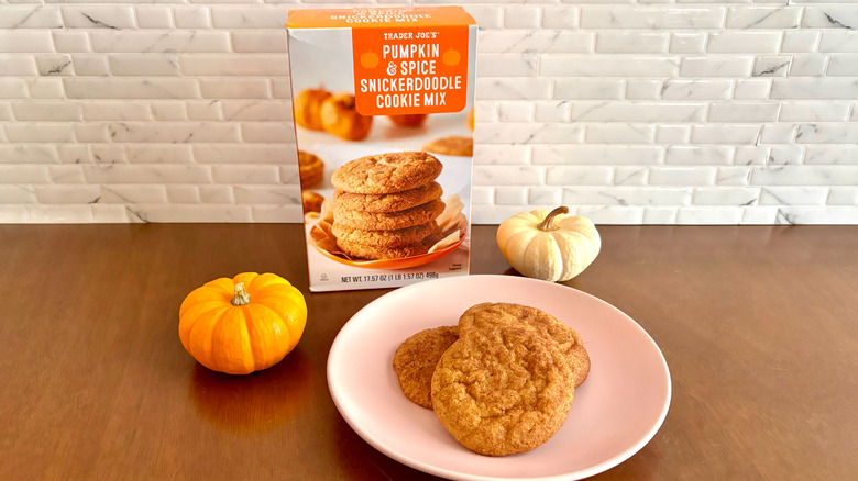 Trader Joe's pumpkin spice snickerdoodle cookie mix box next to cookies on plate and mini pumpkins