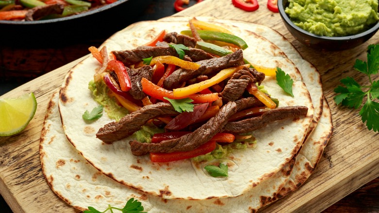 Steak fajitas served with colorful peppers and guacamole