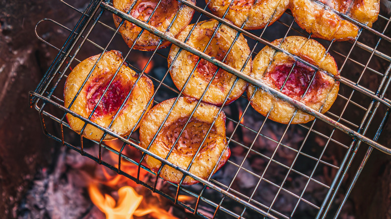 Halved peaches cooking on a grill