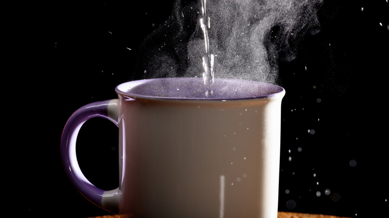 A cup of steaming water against a black background