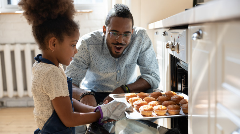Man excited over little girl placing sheet pan into oven