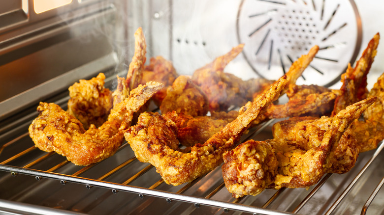 A row of fried chicken wings reheating directly on the rack of an oven