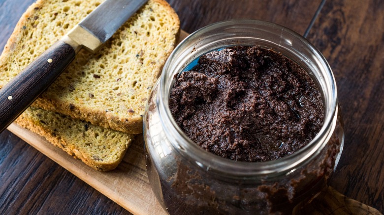 black olive tapenade in jar with knife and bread