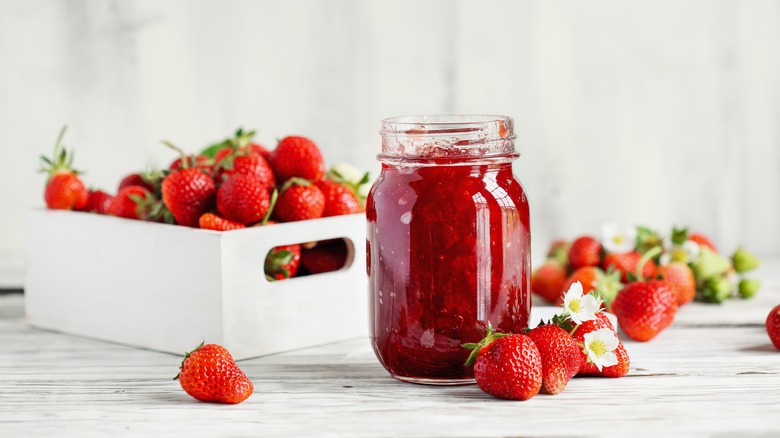 Jelly in jar surrounded by strawberries