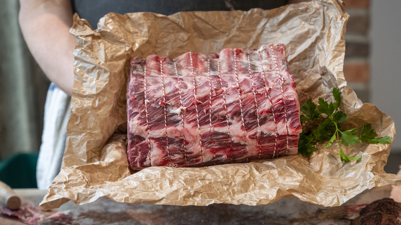 Person holding trussed-up prime rib roast.