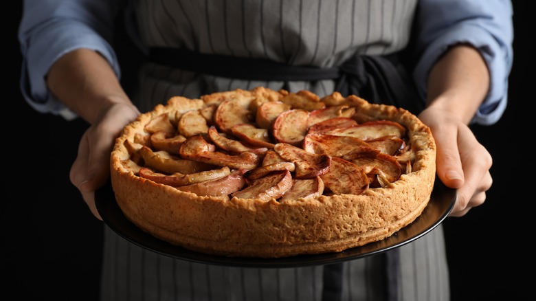 Baker holding a homemade apple pie