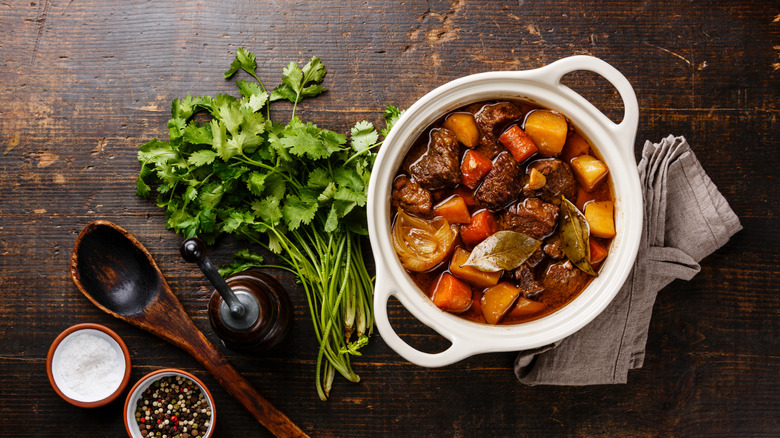 Bowl of beef bourguignon and ingredients on table