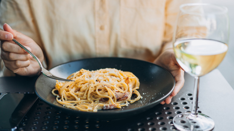 person eating carbonara with wine glass