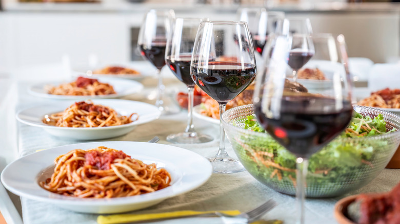 Table with multiple bowls of pasta and wine glasses