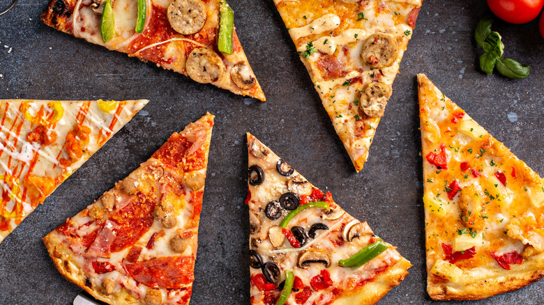 Overhead shot of several different kinds of pizza by the slice.