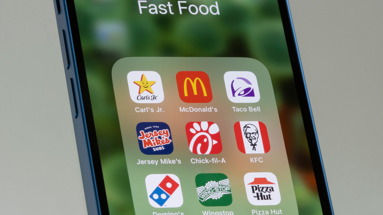 Cell phone with various fast food app icons, including Jersey Mike's and Wingstop