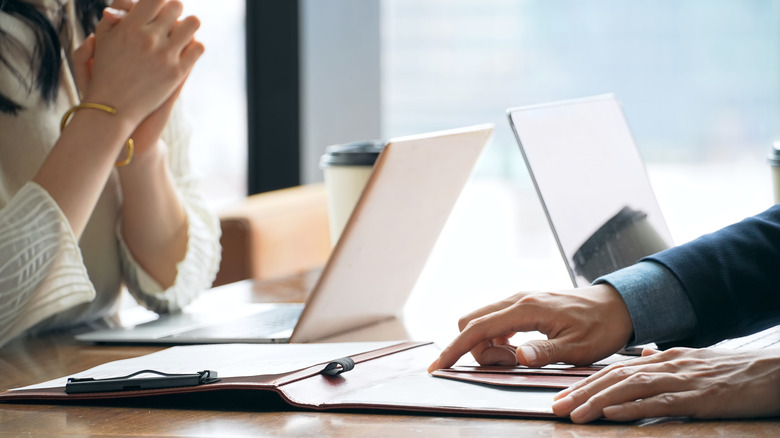People in a professional setting with laptops and paperwork