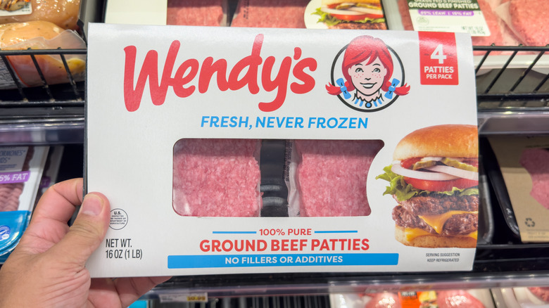 hand holding a package of wendy's fresh, never frozen beef patties in a supermarket