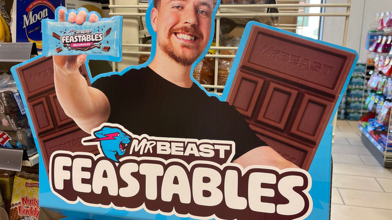 Cardboard cutout of Mr. Beast holding Feastable candy bar in a store