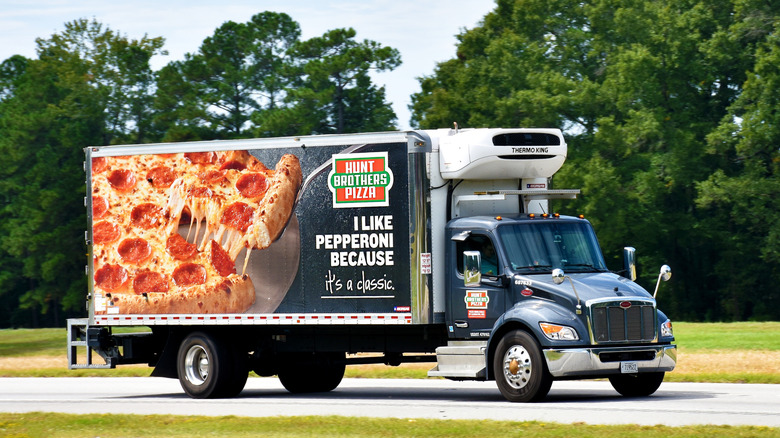 Hunt Brothers Pizza truck on a road with trees behind