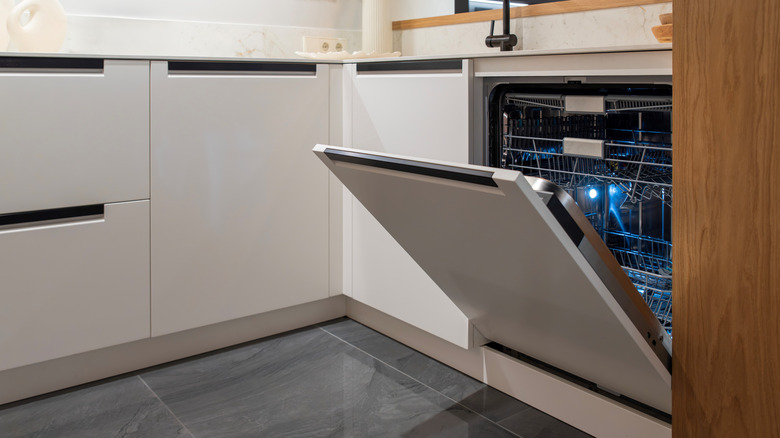 An open dishwasher door in a modern kitchen