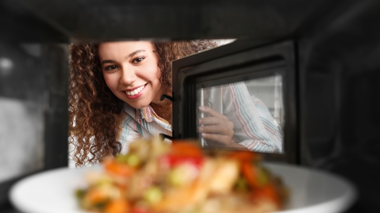 Person reheating leftovers in microwave