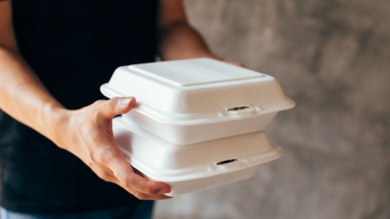 Hands holding styrofoam containers
