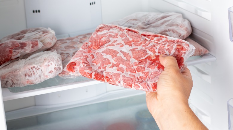 hand grabbing frozen meat from freezer