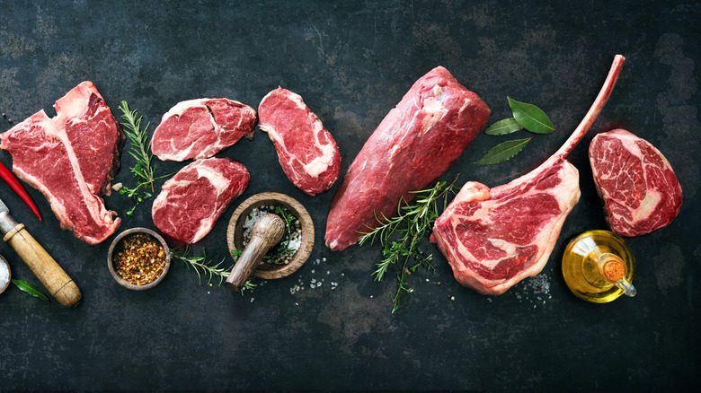 cuts of raw steak with herbs, salt, and oil