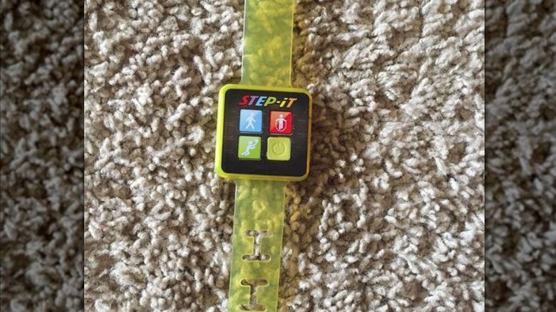 Close up of yellow Step-It fitness tracker on carpet, mirrored image