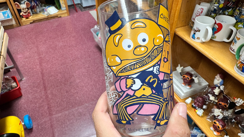 Hand holding Vintage 1977 McDonalds Mayor McCheese Action Series glass cup in store