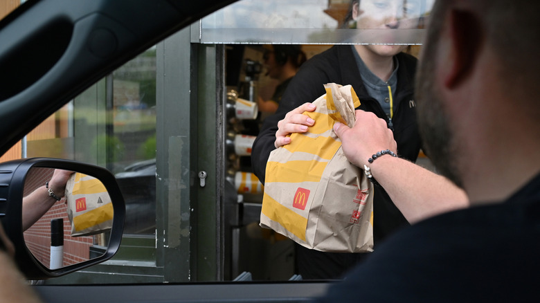 A driver collects a McDonald's order at a drive-through restaurant