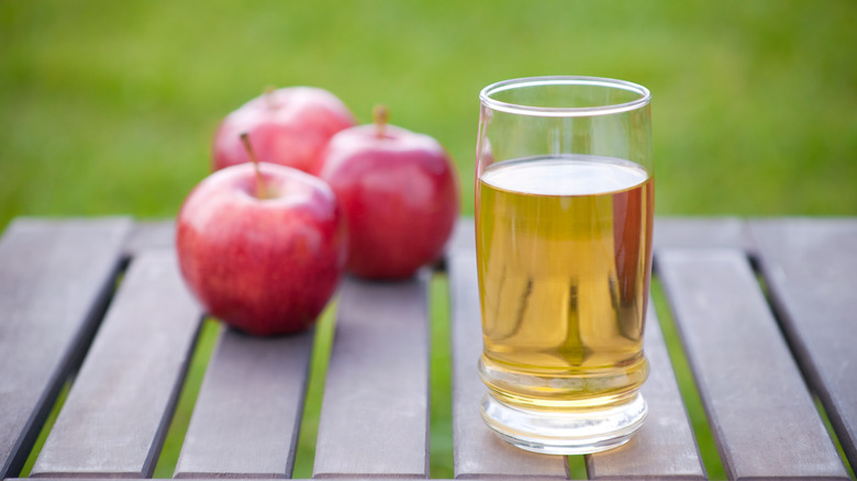 Three apples and a glass of apple juice