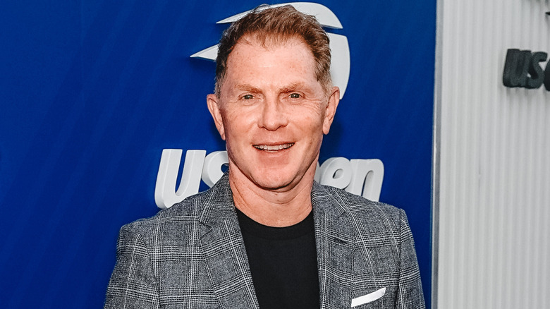 Portrait photo of Bobby Flay in a gray suit against a blue background