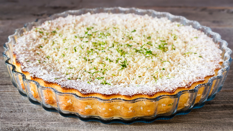 a coconut impossible pie topped with white chocolate shavings and lime zest