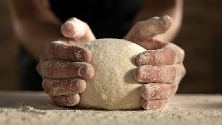 Hands shaping pizza dough