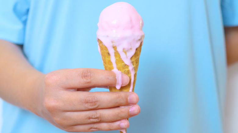 person in blue shirt holding melted ice cream