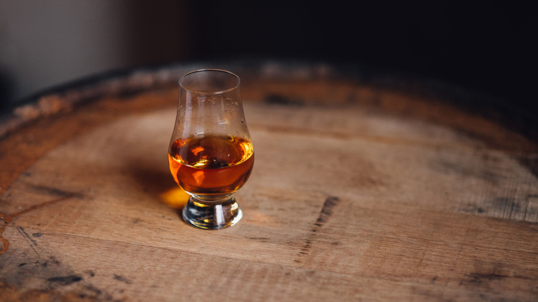 Glencairn glass of whiskey on top of barrel
