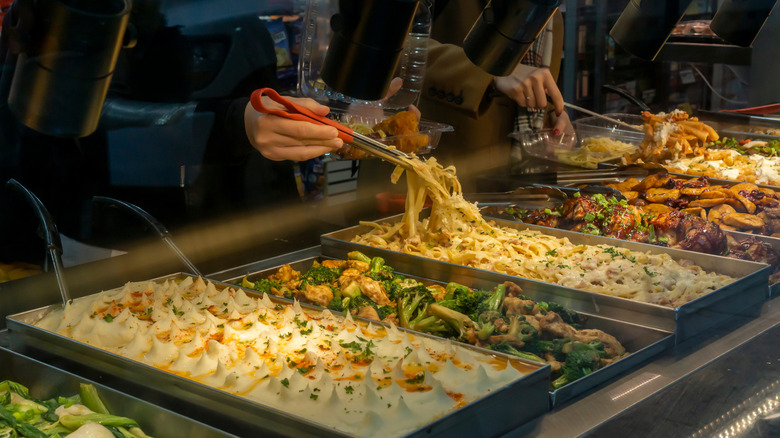 People taking food from a grocery store hot bar