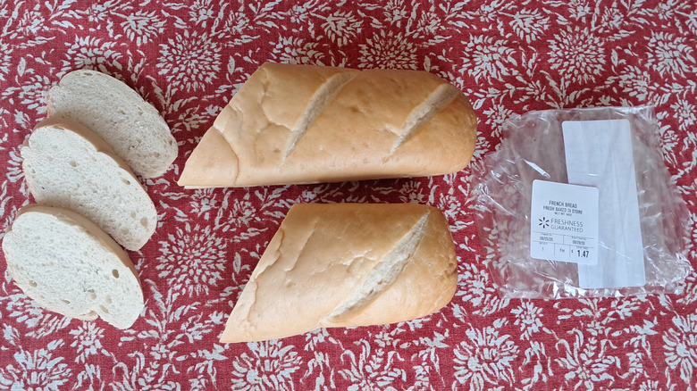 A sliced loaf of Walmart Freshness Guaranteed French Bread against a red patterned tablecloth