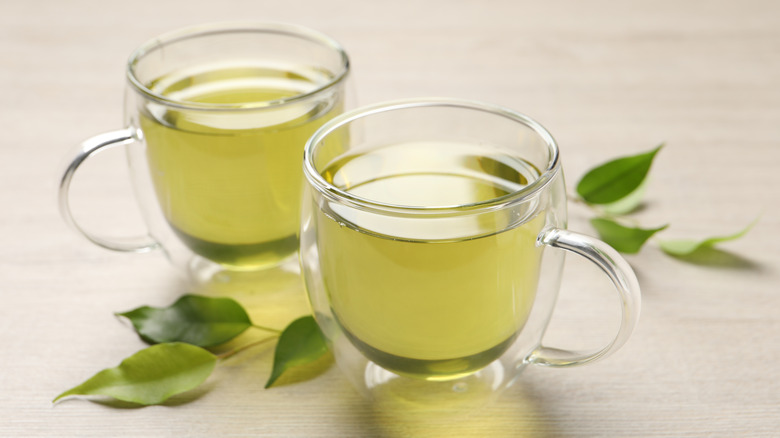 Two glass cups with green tea on table